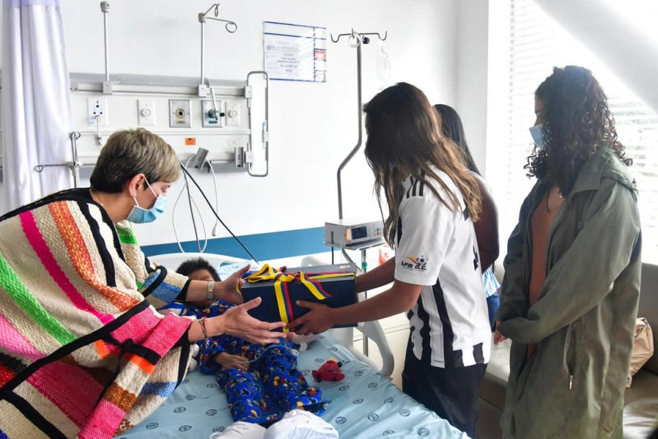 La primera dama colombiana Verónica Alcocer (izquierda) ofrece un regalo a uno de los niños (Presidencia coloombiana/AFP)