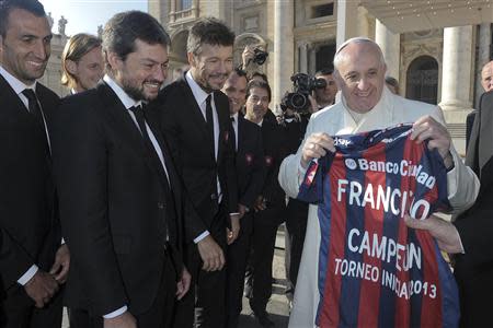 Pope Francis holds a jersey of Argentine soccer team San Lorenzo, given to him as a gift from members of the team, during the Wednesday general audience in St Peter's Square at the Vatican December 18, 2013. REUTERS/Osservatore Romano