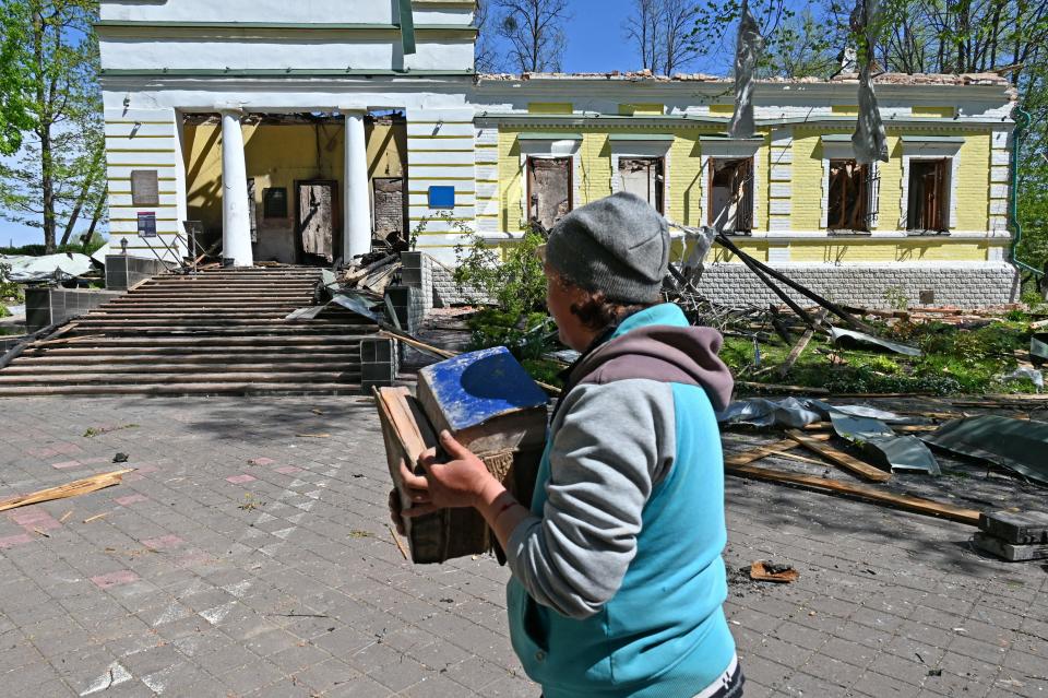 A museum employee carries surviving books from the destroyed building of the Hryhoriy Skovoroda National Literary Memorial Museum  in the village of Skovorodynivka, in Kharkiv Region, on May 7, 2022, on the 73rd day of the Russian invasion of Ukraine. - According to a report from the Kharkiv Regional Military Administration, late evening on May 6, a Russian missile hit on the Hryhoriy Skovoroda National Literary Memorial Museum in the village of Skovorodynivka. As a result of the missile hit, the 17th century manor house was destroyed and burned, where the world-famous Ukrainian philosopher, theologian and poet Hryhoriy Skovoroda (1722-1794) lived and worked in the last year of his life. (Photo by SERGEY BOBOK / AFP) (Photo by SERGEY BOBOK/AFP via Getty Images)