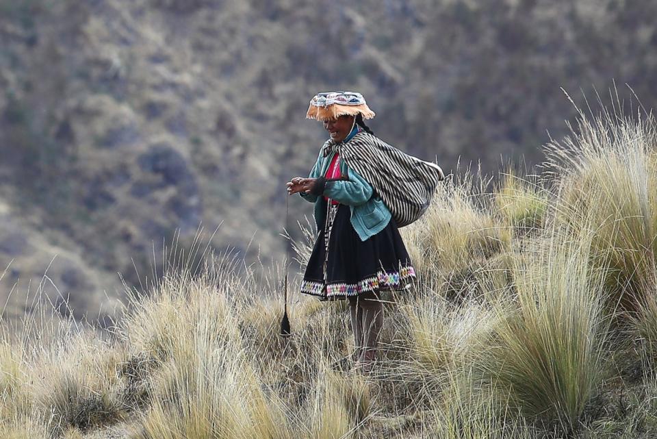 A farmer knitting while watching her heard in the Andean highlands.<p>Photo: Leonardo Fernandez/Getty Images</p>