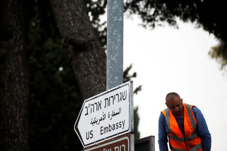 A worker stands next to a road sign directing to the U.S. embassy, in the area of the U.S. consulate in Jerusalem, May 7, 2018. REUTERS/Ronen Zvulun