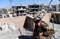 <p>Members of the Syrian Democratic Forces (SDF), backed by US special forces, walk on a building near Raqa’s central hospital as they clear the last positions on the frontline on Oct. 16, 2017 in the Islamic State (IS) group jihadists crumbling stronghold. (Photo: Bulent Kilic/AFP/Getty Images) </p>