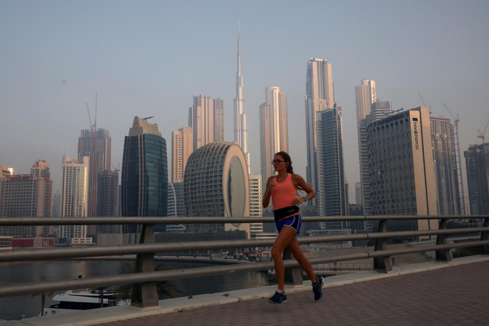 A woman runs past the Burj Khalifa and the downtown skyline in Dubai, United Arab Emirates, June 13, 2021. Picture taken June 13, 2021. REUTERS/Christopher Pike