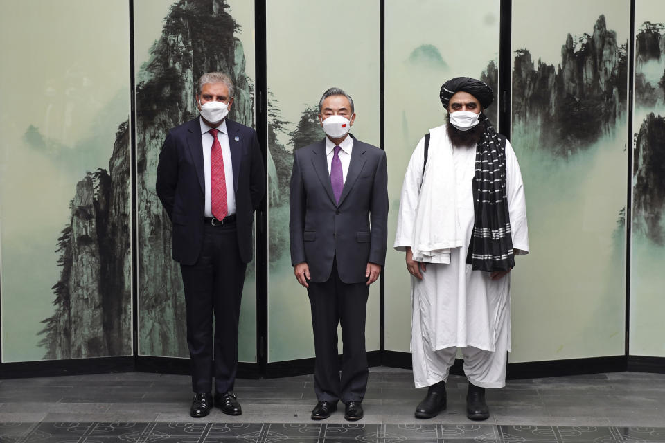 In this photo released by Xinhua News Agency, Chinese Foreign Minister Wang Yi pose for photos next to Pakistan Foreign Minister Shah Mahmood Qureshi at left and Taliban-appointed Afghanistan Foreign Minister Amir Khan Muttaqi at right during a meeting held in Tunxi district in eastern China's Anhui province on Wednesday, March 30, 2022. Chinese leader Xi Jinping on Thursday issued strong backing for Afghanistan at a regional conference, while making no mention of human rights abuses by the country's Taliban leaders. (Zhou Mu/Xinhua via AP)