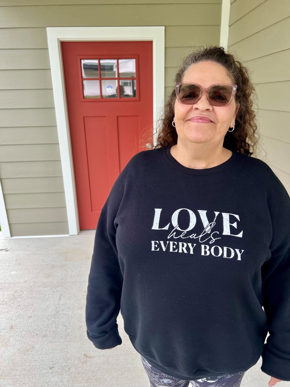 Diana Burke, 57, employee and graduate of Thistle Farms recovery program for women survivors of trafficking and addiction, smiles in front of her new North Nashville house on April 10, 2024. Burke, who'll pay a mortgage, got help from Thistle Farms and other nonprofits to get the home