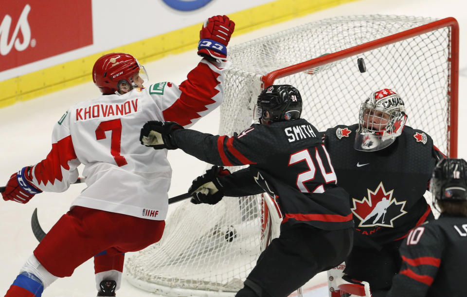 Canada's goaltender Joel Hofer, right, eyes the puck as Canada's Ty Smith, center, challenges Russia's Alexander Khovanov during the U20 Ice Hockey Worlds gold medal match between Canada and Russia in Ostrava, Czech Republic, Sunday, Jan. 5, 2020. (AP Photo/Petr David Josek)