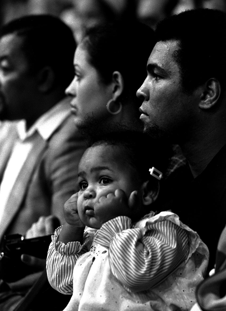<p>15-month-old Hana Ali is shown watching the attractions of the Ringling Bros. Barnum and Bailey Circus on Miami Beach, January 19, 1977, held in the arms of her father, world heavyweight champion Muhammad Ali. Mother Veronica is close by, left, but young Hana seems to have here eyes on a different ring from her parents. (AP Photo/stf) </p>