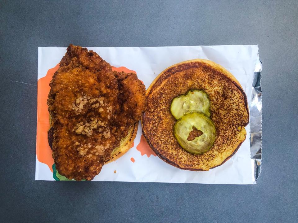 On the left, a bun and chicken fillet from McDonald's crispy chicken sandwich on a white wrapper. On the right, the other bun with two small pickle slices.