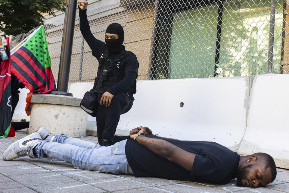 Jimmy Barwan, cousin of Patrick Lyoya, lays on the ground in front of Grand Rapids Police Department as protesters hold a moment of silence for Lyoya in Grand Rapids, Mich. on Thursday, June 9, 2022. A prosecutor filed a second-degree murder charge Thursday against the Michigan police officer who killed Patrick Lyoya, a Black man who was on the ground when he was shot in the back of the head following an intense physical struggle recorded on a bystander's phone. (Joel Bissell/The Grand Rapids Press via AP)