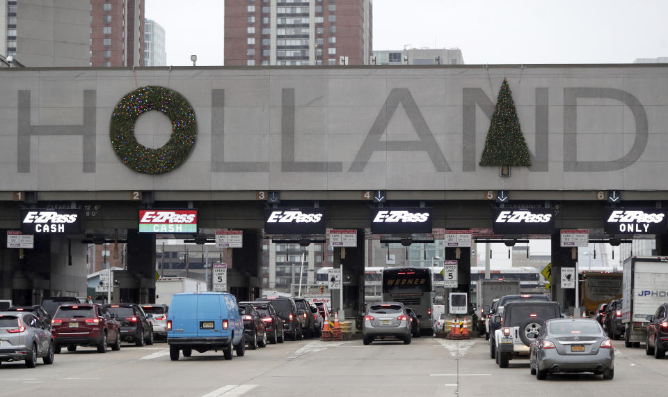 Holiday decorations adorn the letters on the toll booth structure on the Holland Tunnel approach, Thursday, Dec. 13, 2018, in Jersey City. Motorists are complaining that two circular wreaths and another in the shape of a Christmas tree, symmetrically aligned above the tunnel's lanes, don't look right. An online petition suggests placing the tree over the letter "A" instead of the "N". (AP Photo/Julio Cortez)