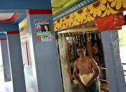 A Hindu priest stands next to a calendar featuring photographs of U.S. President-elect Joe Biden and Vice President-elect Kamala Harris on a wall of the temple where special prayers were held for Harris ahead of her inauguration, in Thulasendrapuram, the hometown of Harris' maternal grandfather, south of Chennai, Tamil Nadu state, India, Wednesday, Jan. 20, 2021. A tiny, lush-green Indian village surrounded by rice paddy fields was beaming with joy Wednesday hours before its descendant, Kamala Harris, takes her oath of office and becomes the U.S. vice president. (AP Photo/Aijaz Rahi)