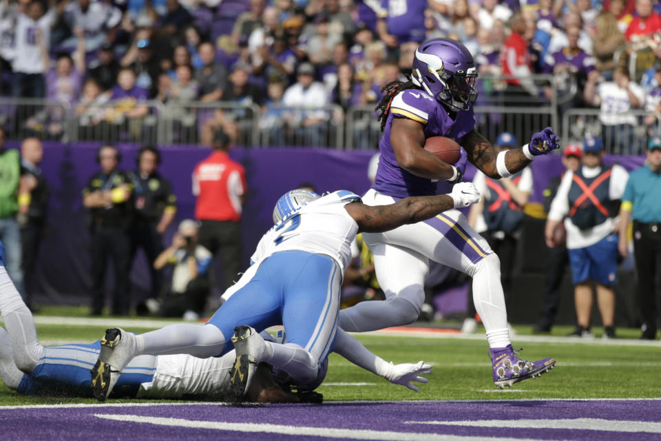Minnesota Vikings running back Alexander Mattison scores on a 6-yard touchdown run ahead of Detroit Lions linebacker Austin Bryant, left, during the second half of an NFL football game, Sunday, Sept. 25, 2022, in Minneapolis. (AP Photo/Andy Clayton-King)