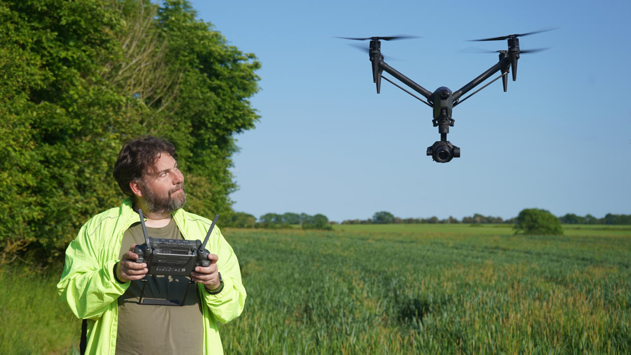  Adam Juniper piloting the DJI Inspire 3 which is near him in a field as part of the DJI Inspire 3 review testing process 