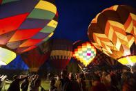 People look at hot air balloons during a night glow on the evening of Day 3 of the Canadian Hot Air Balloon Championships in High River September 27, 2013. Spectators had the opportunity to walk among the balloons which do not actually launch. The launches during the day will determine qualifiers for the World Hot Air Balloon Championships in Sao Paulo in 2014. REUTERS/Mike Sturk (CANADA - Tags: SOCIETY)