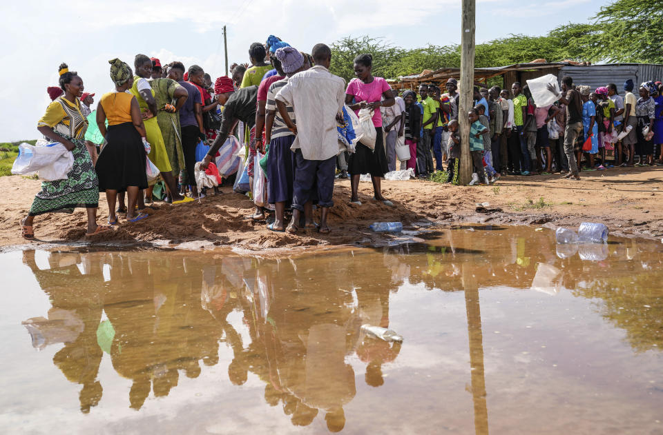 Residents queue for a planned distribution of food, after El Niño rains damaged their houses in Bangale town in Tana River county, Kenya, on Sunday, Nov. 26, 2023. Severe flooding in the country has killed at least 71 people and displaced thousands, according to estimates from the UN Office for the Coordination of Humanitarian Affairs. (AP Photo/Brian Inganga).