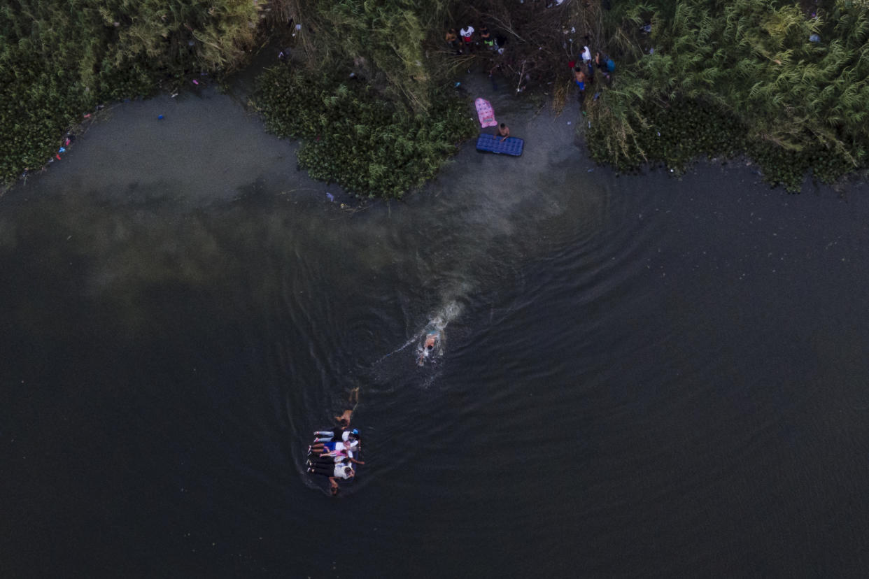 Migrants use a raft to cross the Rio Grande as others wait on the Mexico side of the Texas border, Thursday, May 11, 2023, in Brownsville, Texas. (AP Photo/Julio Cortez)