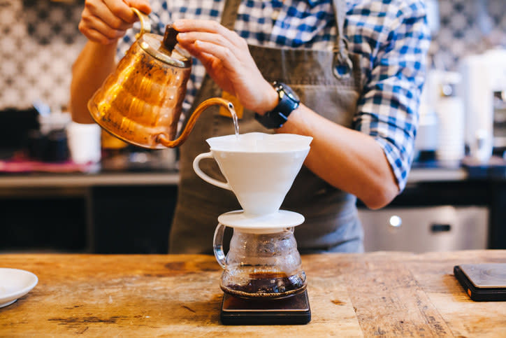 A barista pouring water over a pour over coffee mechanism