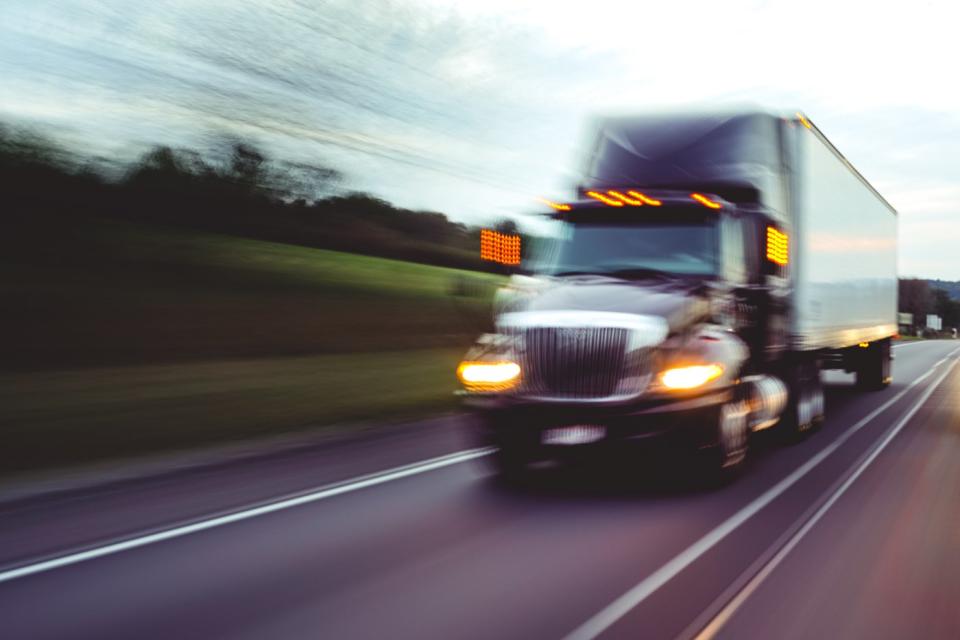 A semi-trucks speeds down the highway, captured by a somewhat blurry picture.