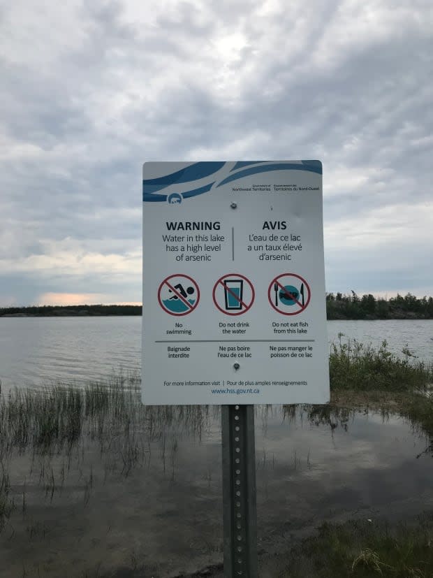 A sign on the Frame Lake trail warns not to swim, drink or eat fish from the lake due to high arsenic levels in June 2018.  (Emily Blake/CBC  - image credit)