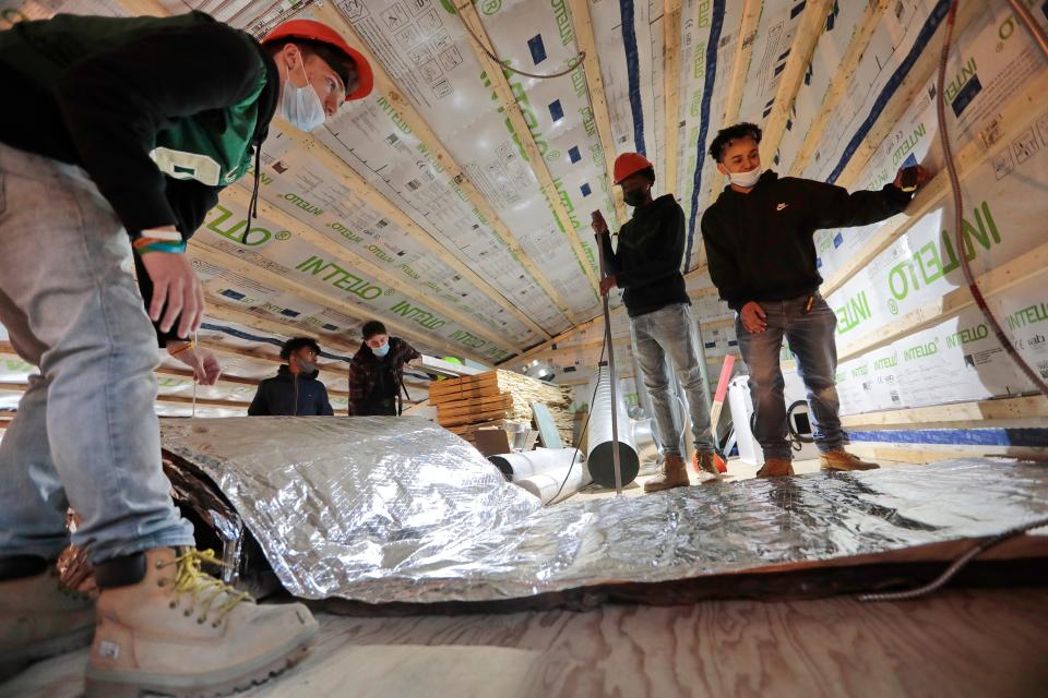 Greater New Bedford Vocational Technical High School students insulate the upper level of a carbon neutral building they are constructing at LLoyd Center for the Environment in Dartmouth.