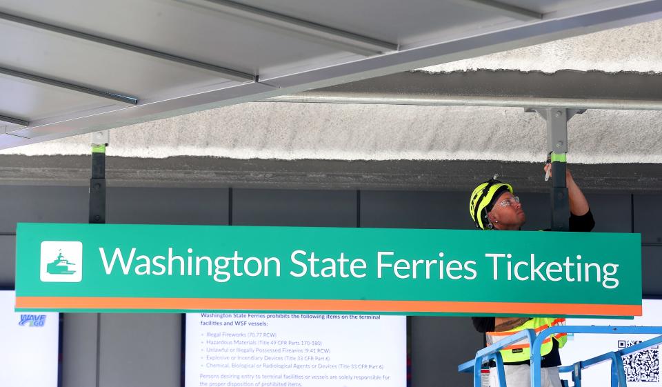 Josh Guynn, with Long Painting, finishes painting above the ticketing booth at the Washington State Ferries terminal at Colman Dock in Seattle on Wednesday.