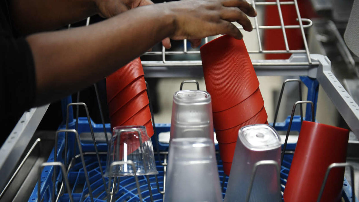 An employee removes reusable dishes and containers from a dishwasher at a McDonald's restaurant in Levallois-Perret, near Paris, on December 20, 2022. - From January 1, 2023, within the framework of the anti-waste law, fast food restaurants must use reusable dishes for on-site orders. (Photo by JULIEN DE ROSA / AFP)