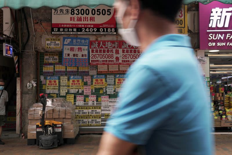 Man walks past a shuttered shop space covered in rental advertisements in Hong Kong's northern town of Sheung Shui