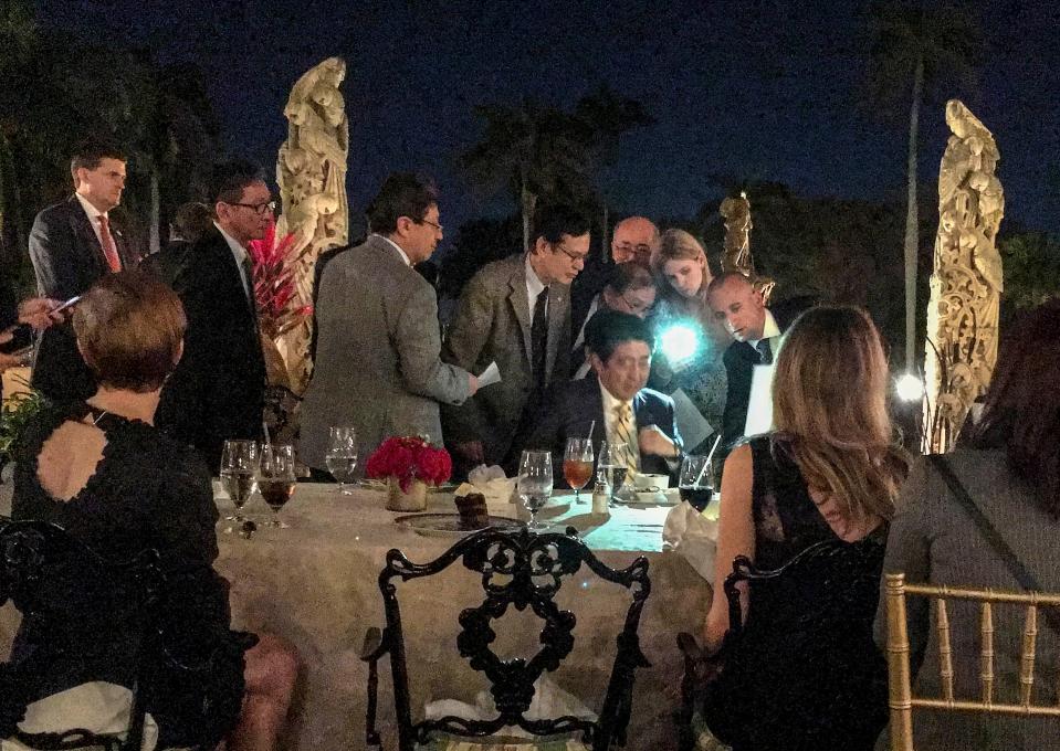 Japanese Prime Minister Shinzo Abe (seated, facing camera) is surrounded by aides after he and President Donald Trump, right, (blocked from view) learned of a missile launch by North Korea during a Feb. 11, 2017, visit at Mar-a-Lago.