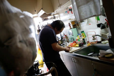 Akihiro Karube, 53, who lives with his widowed 84-year-old dad, cooks in a kitchen at his public housing in Hino, suburb of Tokyo, Japan, February 23, 2017. REUTERS/Toru Hanai