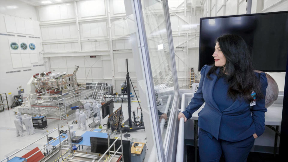 Poet Laureate Ada Limón in a blue suit looking out over a NASA clean room