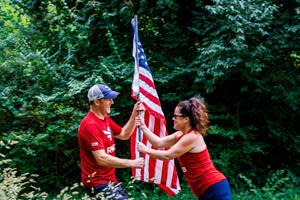 One Team RWB member passes an American flag to another Team RWB member.