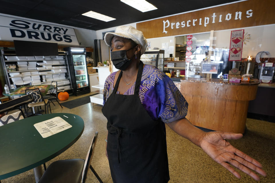 Co-owner of Creative Works Gallery and Cafe, Sarah Mayo, gestures during an interview in Surry, Va., Tuesday, Feb. 9, 2021. Mayo opened the cafe and gallery in an old pharmacy which closed. Mayo kept the pharmacy signs to remind people of what was there. (AP Photo/Steve Helber)