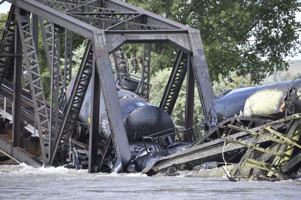 Several train cars are immersed in the Yellowstone River after a bridge collapse near Columbus, Mont., Saturday, June 24, 2023. The bridge collapsed overnight, causing a train that was traveling over it to plunge into the water below. Authorities on Sunday were testing the water quality along a stretch of the Yellowstone River where mangled cars carrying hazardous materials remained after crashing into the waterway. (AP Photo/Matthew Brown)