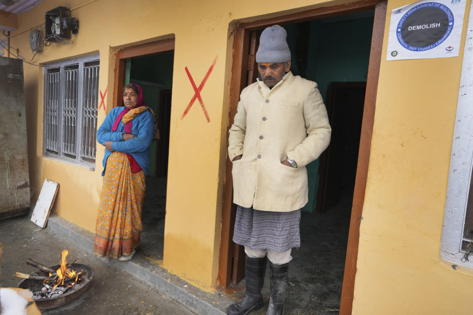 Chandra Pandey and his wife stand outside their home marked with a red cross and soon to be demolished, in Joshimath, in India's Himalayan mountain state of Uttarakhand, Friday, Jan. 20, 2023. For months, residents in Joshimath, a holy town burrowed high up in India's Himalayan mountains, have seen their homes slowly sink. They pleaded for help, but it never arrived. In January however, their town made national headlines. Big, deep cracks had emerged in over 860 homes, making them unlivable. (AP Photo/Rajesh Kumar Singh)