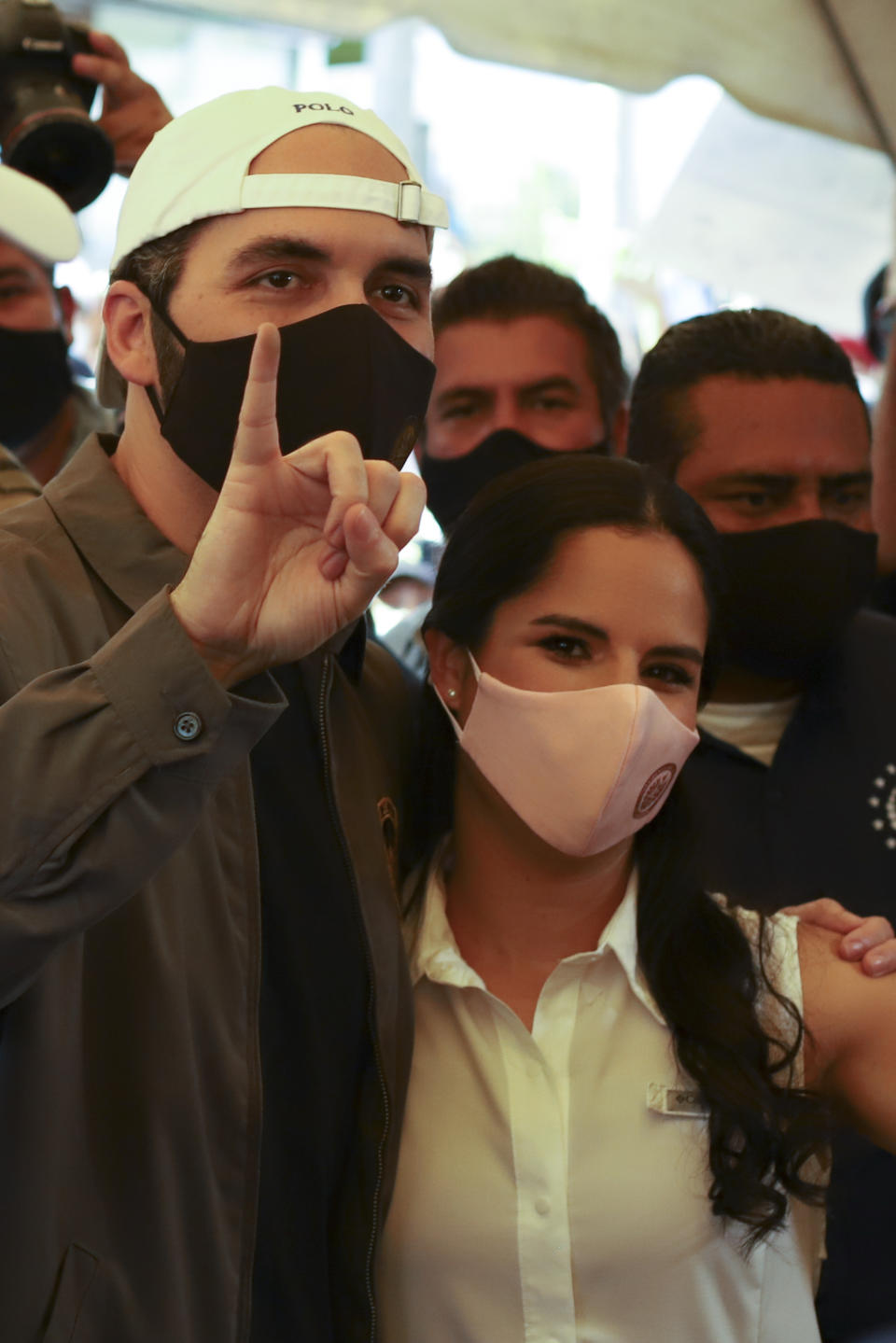 President Nayib Bukele holds up his marked finger after voting, as he poses with his wife Gabriela Rodriguez de Bukele at a polling station during local and legislative elections, in San Salvador, El Salvador, Sunday, Feb. 28, 2021. (AP Photo/Salvador Melendez)