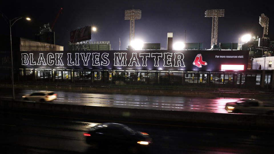 Cars along the Massachusetts Turnpike drive past a giant "Black Lives Matter" mural, Wednesday evening, July 22, 2020, outside Fenway Park, at the rear, in Boston. (AP Photo/Charles Krupa)