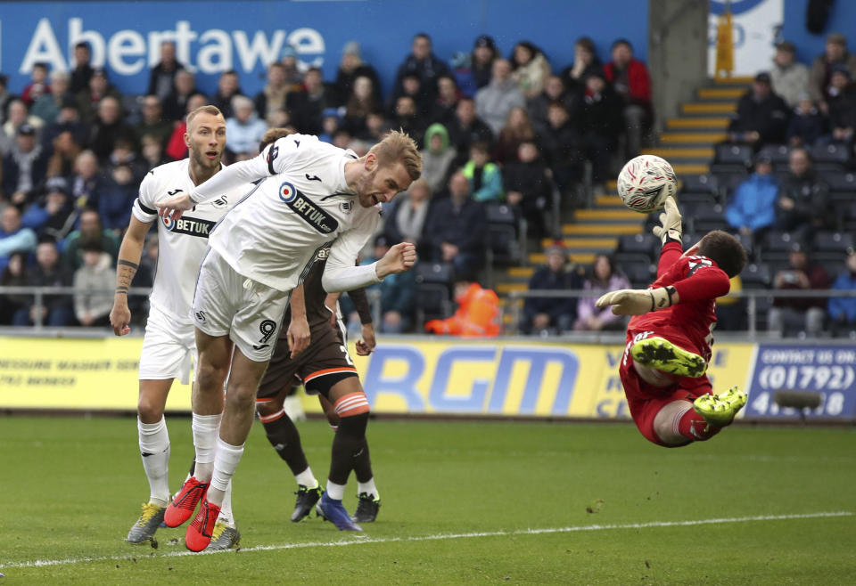 El jugador del Swansea City, Oliver McBurnie, remata de cabeza, pero el portero del Brentford, Luke Daniels, ataja el balón durante su partido de la quinta ronda de la Copa FA en el estadio Liberty en Swansea, Inglaterra, el domingo 17 de febrero de 2019. (Nick Potts/PA vía AP)