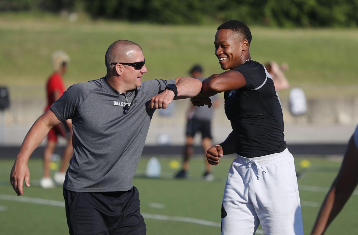 With social distancing in mind, bead football coach Bob Wager, left, and linebacker Morice Blackwell greet each other with elbow taps during the strength and conditioning camp at Arlington Martin High School on June 18, 2020 in Arlington, Texas. While states have been easing the economic and social lockdowns prompted by the coronavirus pandemic, some are now letting high school athletes return for summer workouts before teachers have even figured out how they are going to hold classroom instruction.