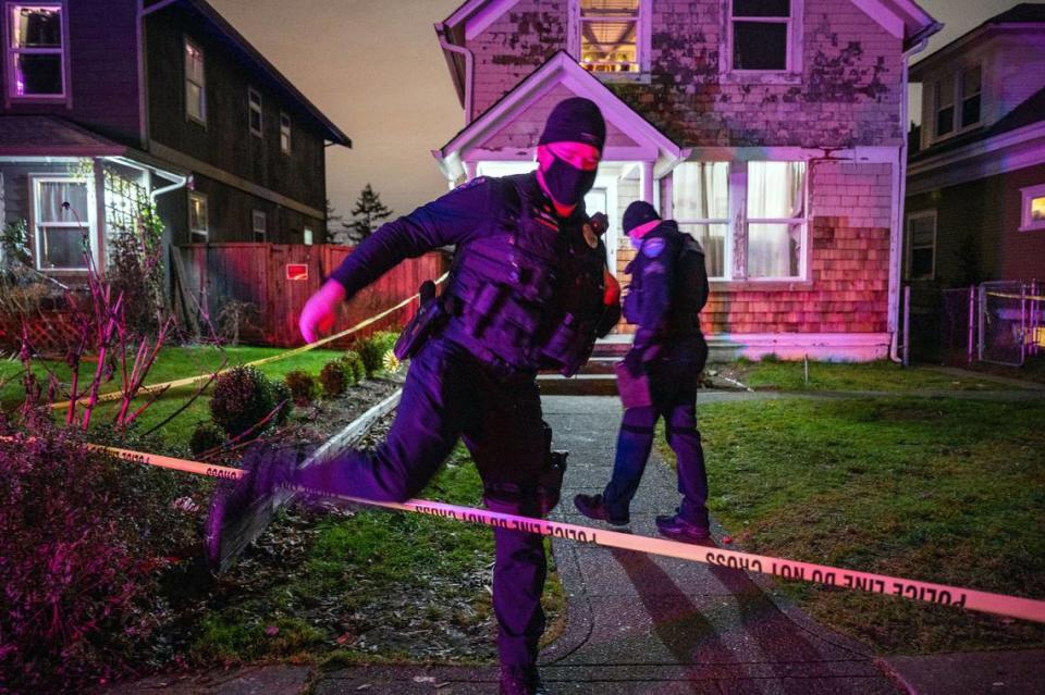 An officer from the Tacoma Police Department steps over crime scene tape as law enforcement investigates the scene of a shooting in the 800 block of South Sheridan Avenue in Tacoma, Wash., on Monday, Jan. 17, 2022. According to a tweet earlier in the evening from the Tacoma Police Department: “At 5:41 p.m. South Sound 911 received a call from the 800 blk of S Sheridan Ave. saying a male had been shot. Officers located an unresponsive male who was transported to a local hospital where he died from his injuries.”