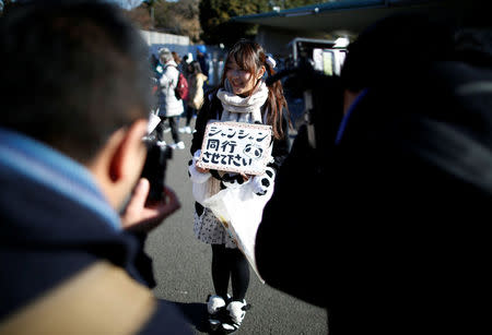 Panda enthusiast Saeko Nishitani, 23, poses for a photograph after watching the public viewing of female baby panda Xiang Xiang, born from mother panda Shin Shin on June 12, 2017, on the first day of her public debut at Ueno Zoological Gardens in Tokyo, Japan December 19, 2017. Placard reads, 'Take me to the public viewing of the panda Xiang Xiang'. REUTERS/Issei Kato