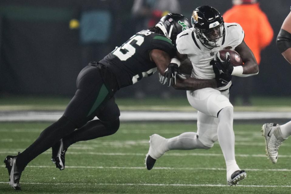 Jacksonville Jaguars running back Travis Etienne Jr. (1) tries to avoid a tackle by New York Jets linebacker Quincy Williams (56) during the first quarter of an NFL football game, Thursday, Dec. 22, 2022, in East Rutherford, N.J. (AP Photo/Seth Wenig)