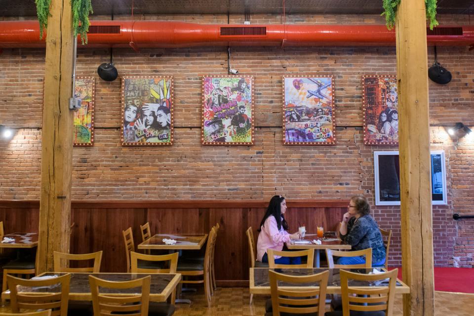 Posters of popular Bollywood celebrities hang on a wall in the main dining area of the new Indian restaurant Bollywood Bites Bistro & Event Center in downtown Peoria.