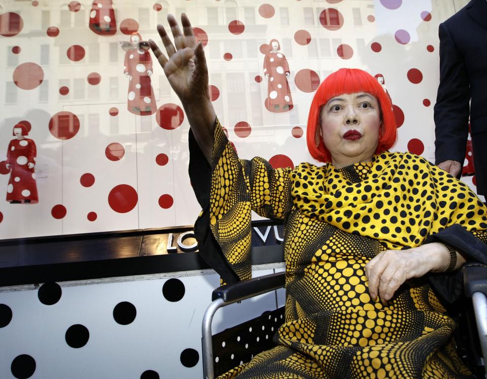 Artista Yayoi Kusama waves to fans in front of the windows of Vuitton's flagship store for the unveiling of a new collaborative collection by Vuitton creative designer Marc Jacobs and Kusama in New York, Tuesday, July 10, 2012. (AP Photo/Kathy Willens)