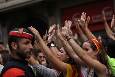 People raise their hands beside a Catalan regional police officer during a demonstration two days after the banned independence referendum in Barcelona, Spain, October 3, 2017. REUTERS/Susana Vera