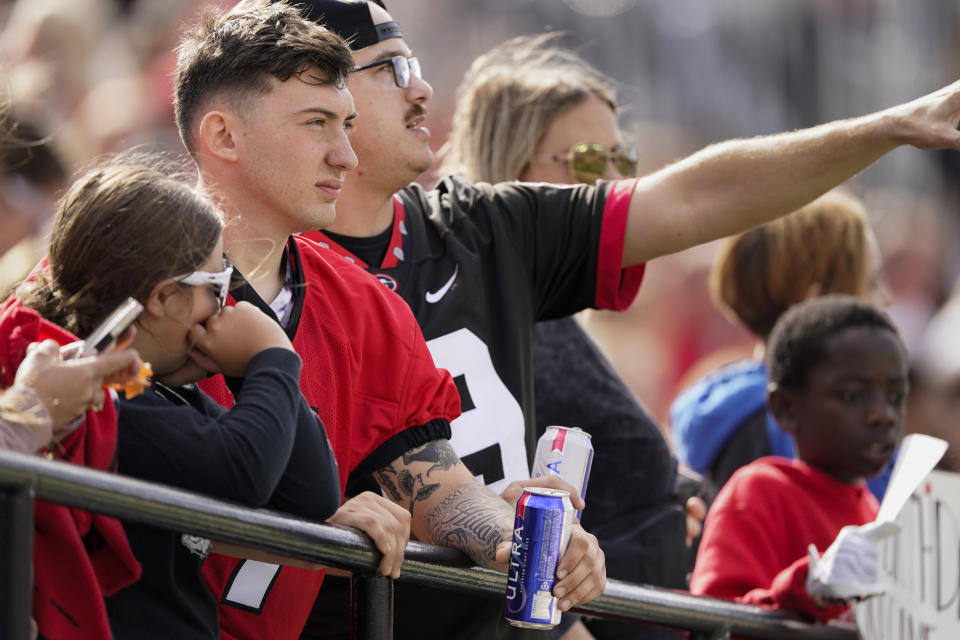 A Georgia fan holds a beer while watching an NCAA college football game against Vanderbilt, Saturday, Oct. 14, 2023, in Nashville, Tenn. For many years in college football, the booze flowed only outside the stadiums at tailgates. Not anymore. Selling beer and wine has become the norm. According to a survey by The Associated Press of Power Five conference schools and Notre Dame, 55 of 69 of them sell alcohol in the public areas of their stadiums on game days. (AP Photo/George Walker IV)