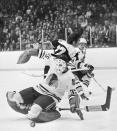 FILE - In this Feb. 18, 1973, file photo, Chicago Blackhawks' Tony Esposito (35) drops to his knees to stop the puck shot by Boston Bruins' Derek Sanderson (27) during the first period of an NHL hockey game in Chicago. Esposito, a Hall of Fame goaltender who played almost his entire 16-year career with the Blackhawks, has died following a brief battle with pancreatic cancer, the team announced Tuesday, Aug. 10, 2021. He was 78. (AP Photo/Fred Jewell)