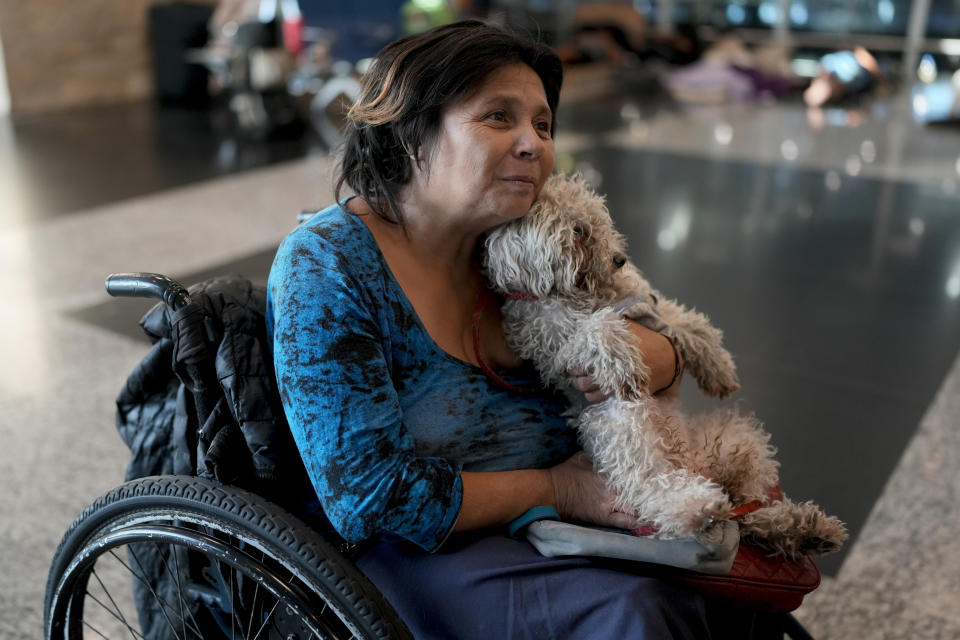 Laura Cardozo holds her dog inside the Jorge Newbery international airport, commonly known as Aeroparque, in Buenos Aires, Argentina, Thursday, April 6, 2023. Homeless, Cardozo and her two dogs sleep at Aeroparque each night. (AP Photo/Natacha Pisarenko)