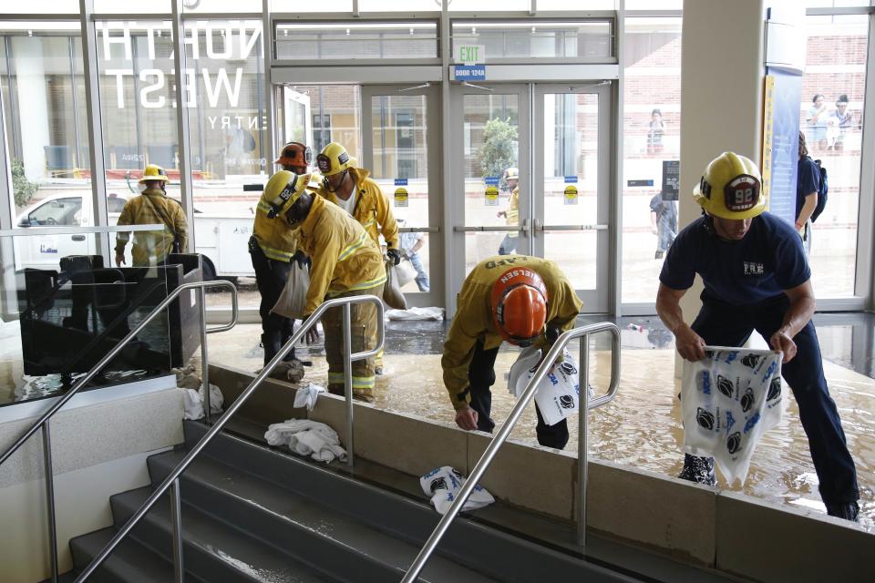 Firefighters work to dam up a stairway inside UCLA's Pauley Pavilion sporting arena as water flows from a broken thirty inch water main that was gushing water onto Sunset Boulevard near the UCLA campus in the Westwood section of Los Angeles July 29, 2014. The geyser from the 100-year old water main flooded parts of the campus and stranded motorists on surrounding streets. REUTERS/Danny Moloshok