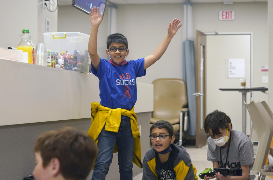 Ronan Kotiya, left, raises his arms after his toy car won a race with his brother Keaton Kotiya, center, and Alex Oliver during a workshop for young caregivers of ALS diagnosed family members in Dallas, Texas, Saturday, April 9, 2022. The children have gathered for a clinic to learn more about caring for people with Lou Gehrig's disease, or amyotrophic lateral sclerosis. It's a fatal illness that attacks nerve cells that control muscles throughout the body. (AP Photo/LM Otero)