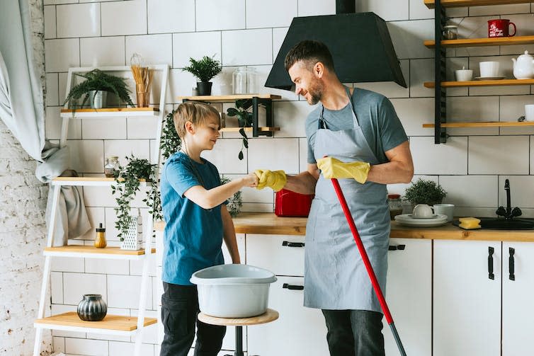 Young dad and son do kitchen chores together